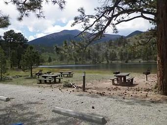 Picnic tables near lake with mountains in background