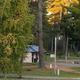 Wide view of the campground entrance and sign with campsites and trees visible — good overall property overview suitable for a gallery (used as site background/hero).