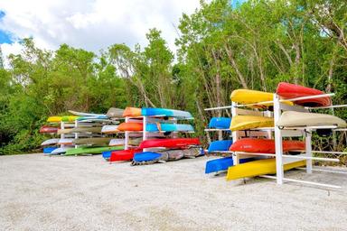 Colorful stacked kayaks/canoes on racks beside natural vegetation — depicts on-site water activity equipment/storage shown in the community gallery.