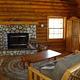 View of the Hillside Cabin's living room with stone fireplace and futon, and cabinent.