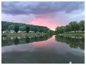 Scenic lakeside view at sunset with RVs reflected in the water — useful for showcasing the campground’s waterfront setting (Overview page image).