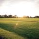 Wide shot of open grassy campground with pavilion, courts and scattered RVs at sunset — from the property's 'Nearby Attractions' gallery and useful to show on-site recreational space.