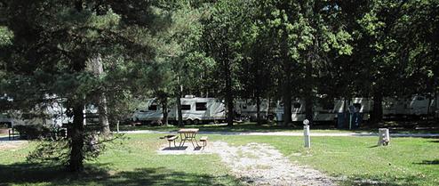Panoramic shot of an RV campsite row with utility pedestals and picnic table — clearly depicts the park’s RV facilities referenced on the site’s family campground/RV park page.