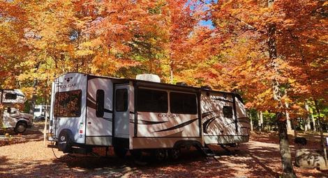 RV in a wooded campsite during fall foliage — a distinct seasonal view of campsite RV accommodations referenced in the property's 'ways to stay' gallery.