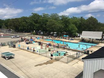 High-detail view of the main outdoor swimming pool with people and surrounding facilities — demonstrates a major on-site amenity and activity area.