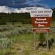 Sign for the group camground area in a location with green grasses, sagebrush, and pine trees in the background. 