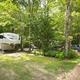 RV campsite among trees with vehicle and gravel roadway — useful view of typical RV/campsite layout (from the rates/reservations campsite gallery).