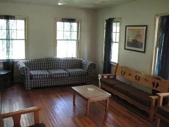 Cabin living room with couch, three person bench, coffee table and chairs.