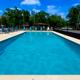 Clear, wide photo of the campground swimming pool area with lounge chairs, fencing, and campground buildings visible in background — suitable to show on-site pool amenity (source: site homepage).