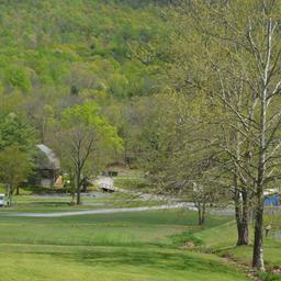 Wide grassy grounds and campground roads with buildings and tree-covered hills in background — useful aerial/landscape overview of the park layout (used on the site homepage).