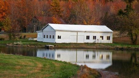 Barn or outbuilding reflected in the pond — provides a distinct architectural feature and broader view of the property grounds (included on the venue site).
