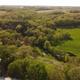 Aerial of the glampgrounds — the creek winding through the wooded property past the dome