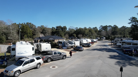 Wide-angle view of an RV row and campground circulation road, showing site spacing and surrounding vegetation — matches gallery images of the property.