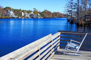 Wooden dock with rocking chair overlooking the waterway — strong scenic shot of the campground pond/Intracoastal frontage featured on the site.