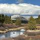 Bunsen Peak under cumulus clouds with a creek in the foreground. The trailhead for Bunsen Peak is not far from Indian Creek Campground