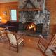 Cozy cabin/lodge interior with wood paneling and stone fireplace — represents lodging common room/amenities on the property (used in lodging/gallery pages).