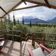 Deck-level daytime view from a tent showing Adirondack chairs and expansive mountain valley scenery — demonstrates guest viewpoint, private deck and the landscape setting guests experience.