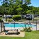 Swimming pool with RVs in the background, surrounded by trees.
