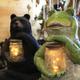 Close-up of decorative frog and bear lantern figures inside a wooded interior — likely from the campground’s on-site store or office gift area (visible on the property home page, shows on-site amenities/merchandise).