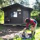 Person making teepee of sticks in a rock firepit in front of Shakes Slough 1 Cabin 