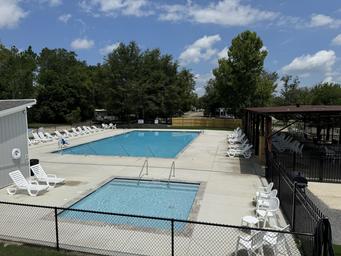 Clear view of the campsite swimming pool area with lounge chairs and covered seating — useful facility photo that appears to be on the resort property.