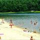 Beach scene with people swimming and sandy shoreline — demonstrates the on-site beach and waterfront recreation available at the property.