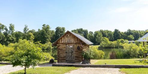 Frontal view of the same lakeside cabin and surrounding landscaping with wider framing — useful overview of cabin placement on the property (used as background/home header images).