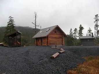 Middle Ridge Cabin on gravel drive with outhouse and woodshed