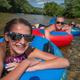 kids floating in tubes on the river in a shallow area by the beach
