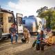 Four people and dogs beside an open campervan and an Airstream at Beach RV Pleasure Point.