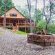 Exterior view of a lodge on-site with wrap‑around porch, firepit and wooded grounds — matches the property’s lodges page and shows outdoor guest facilities and setting.