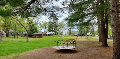 Open grassy campground area with playground equipment and multiple RV sites visible — useful for showing the campground layout and family amenities (from the amenities/images on the site).
