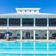 Wide frontal shot of the clubhouse building with the main resort pool in foreground — demonstrates main amenity and architecture (used on the home page).