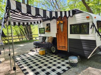 Decorated travel trailer/RV site with awning and gravel pad visible — useful to show the RV campsite setup and ambiance.