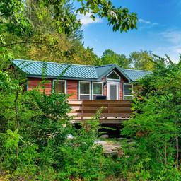 Cabin set in wooded surroundings with porch and deck—clear photograph of the campground’s cabin accommodations (matches 'ways to stay' cabin images on the property page).