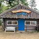 Small log-style building with a 'Lake Pemaquid' sign above the door — identifies on-site facilities and branding, useful for guests locating marina/office (Lake/Marina page).