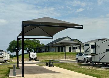 covered paved RV site with clubhouse in the background at The Hill Top