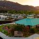 Panoramic hero-style photo at sunset showing the resort clubhouse, RV sites and nearby hotel with hills in background — good wide context and atmosphere.