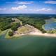 Aerial overview of the campground peninsula showing the beach, treed campsites, access road and marshland — good overall property context; sourced from the campground page.