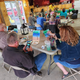 Indoor recreation/crafts scene showing guests painting at tables in a rustic building — matches the campground’s listed activities and appears on the campground’s activities section.