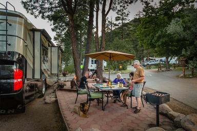 Patio/rv-site scene showing an RV, outdoor dining area and site hardscape — demonstrates a furnished RV/patio option and guest experience at the campground.