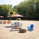 A picnic table and chairs are sitting on a sandy beach next to a fire pit.