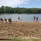 Beach and roped swimming area on the lake with people enjoying the water — highlights waterfront amenities and recreation; shown on the Home page.