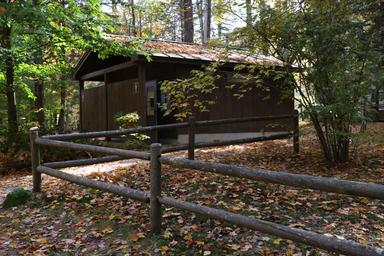 Exterior of a campground restroom/building set in woods — shows on-site facilities and their wooded setting (from Amenities page).