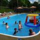 Clear, high-resolution photo of the campground swimming pool with guests and pool-side seating — directly supports facility/amenities on the Events page (shows pool area and surroundings).