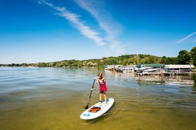 Waterfront scene with paddleboarder and nearby boat docks; illustrates beach/lake access and on-site docks seen in site images.