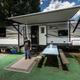 Close view of an RV site with awning, picnic table and mat — represents typical campsite setup and site amenities (gallery image on the campground website).