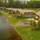 Aerial daytime view of lakeside glamping tents aligned along the water with shore, paths and trees — good overall layout/setting shot (matches site’s 'tents' stay imagery).