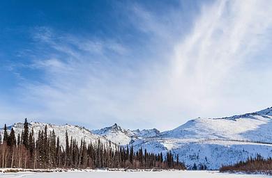 A frozen river and mountains under a blue sky