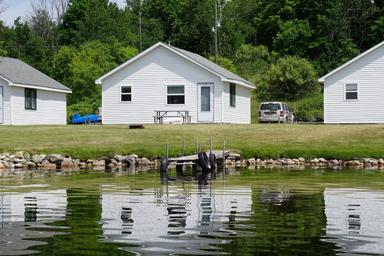 Close lakefront cabin façade with picnic table and dock reflected in the water — clear representation of the property's lakefront cabins (from the cottages page).